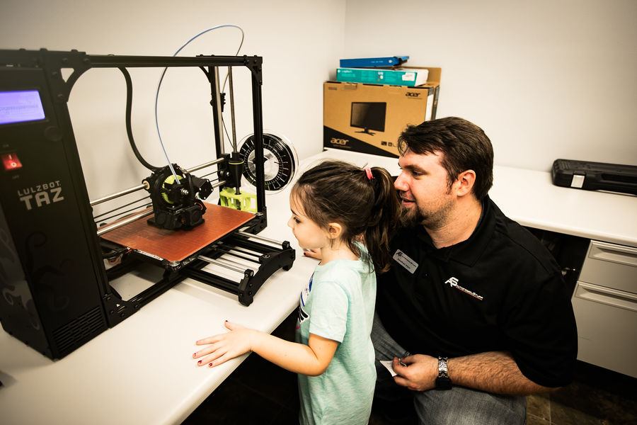 Man showing a child a 3D printer
